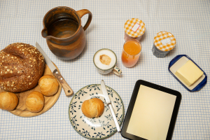 Frühstückstisch mit Brot, Brötchen, Butter, Kaffee, Saft und Marmelade